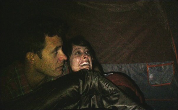 Bryce Johnson and Alexie Gilmore hide from Bigfoot in a scene from Bobcat Goldthwait's film "Willow Creek"